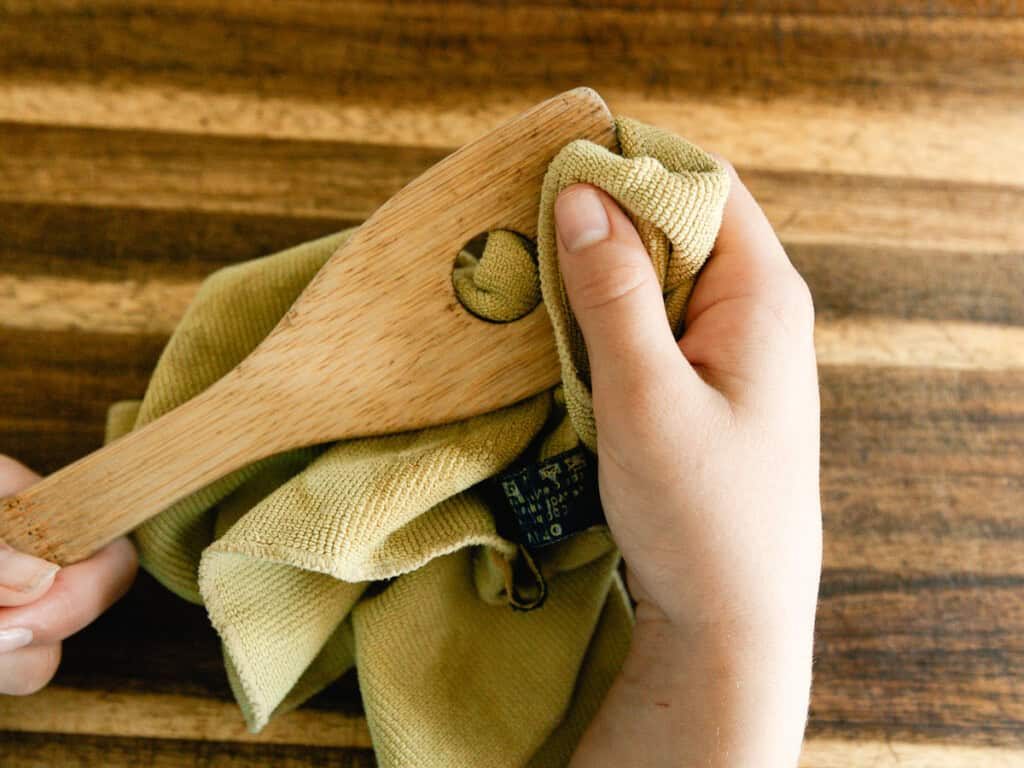 Rubbing wood balm into a wooden spoon with a cloth.