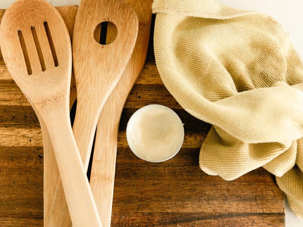 Homemade wood balm on a wooden cutting board with wooden utensils next to it.