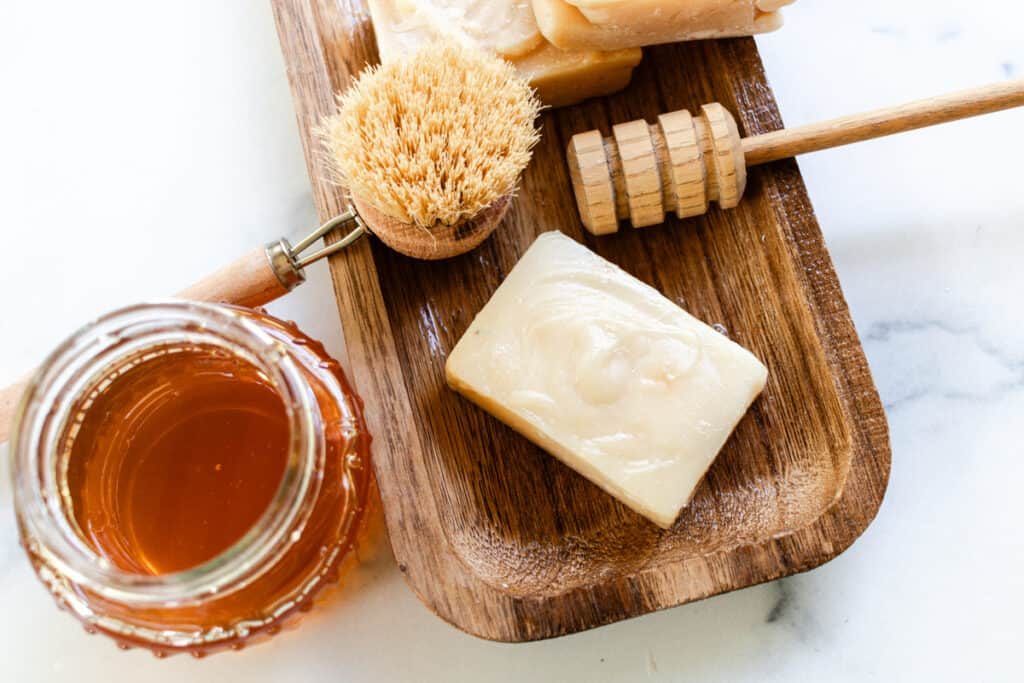 Honey soap bars with scrubbing materials and a jar of honey.