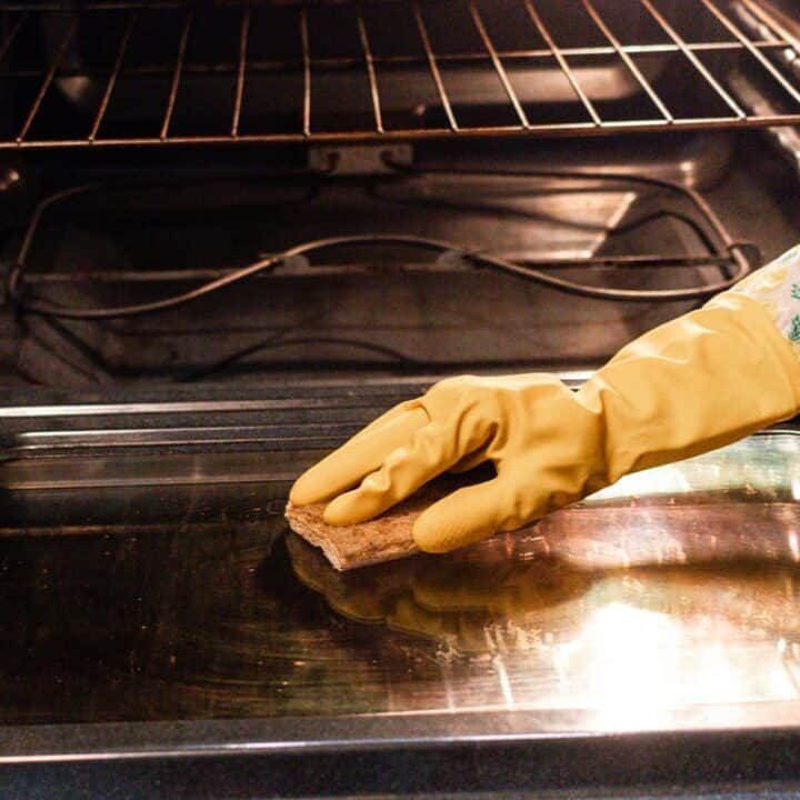 Wiping an oven clean with a sponge after steam cleaning.