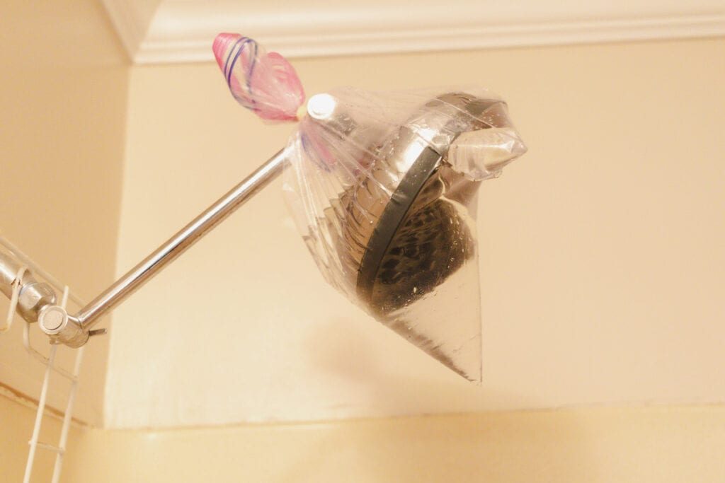 Soaking the hard water buildup in a shower head nozzle in vinegar to loosen it up.