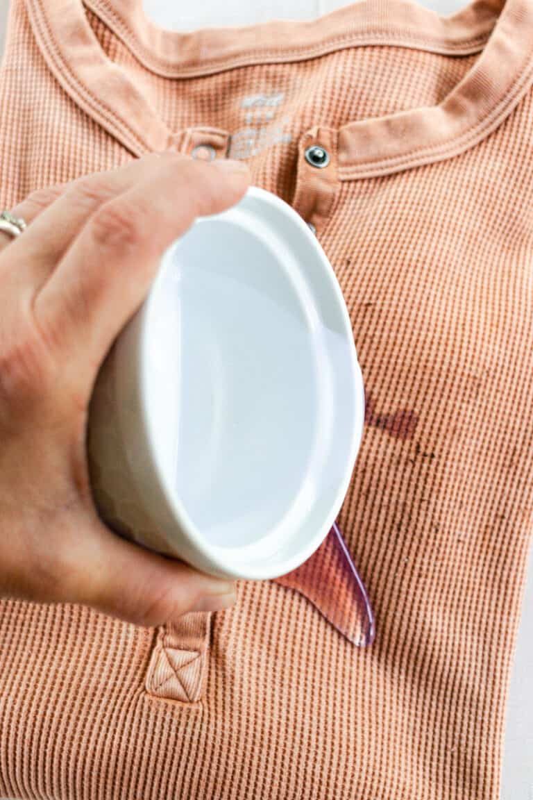 Pouring mold remover onto a clothing item.