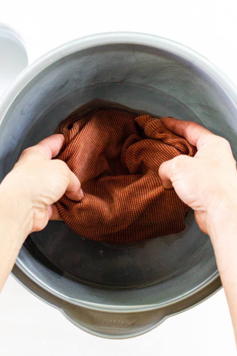 Soaking clothing in a bowl of mold remover.