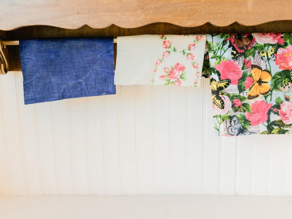Three beeswax wraps hanging off a wooden drying rack.