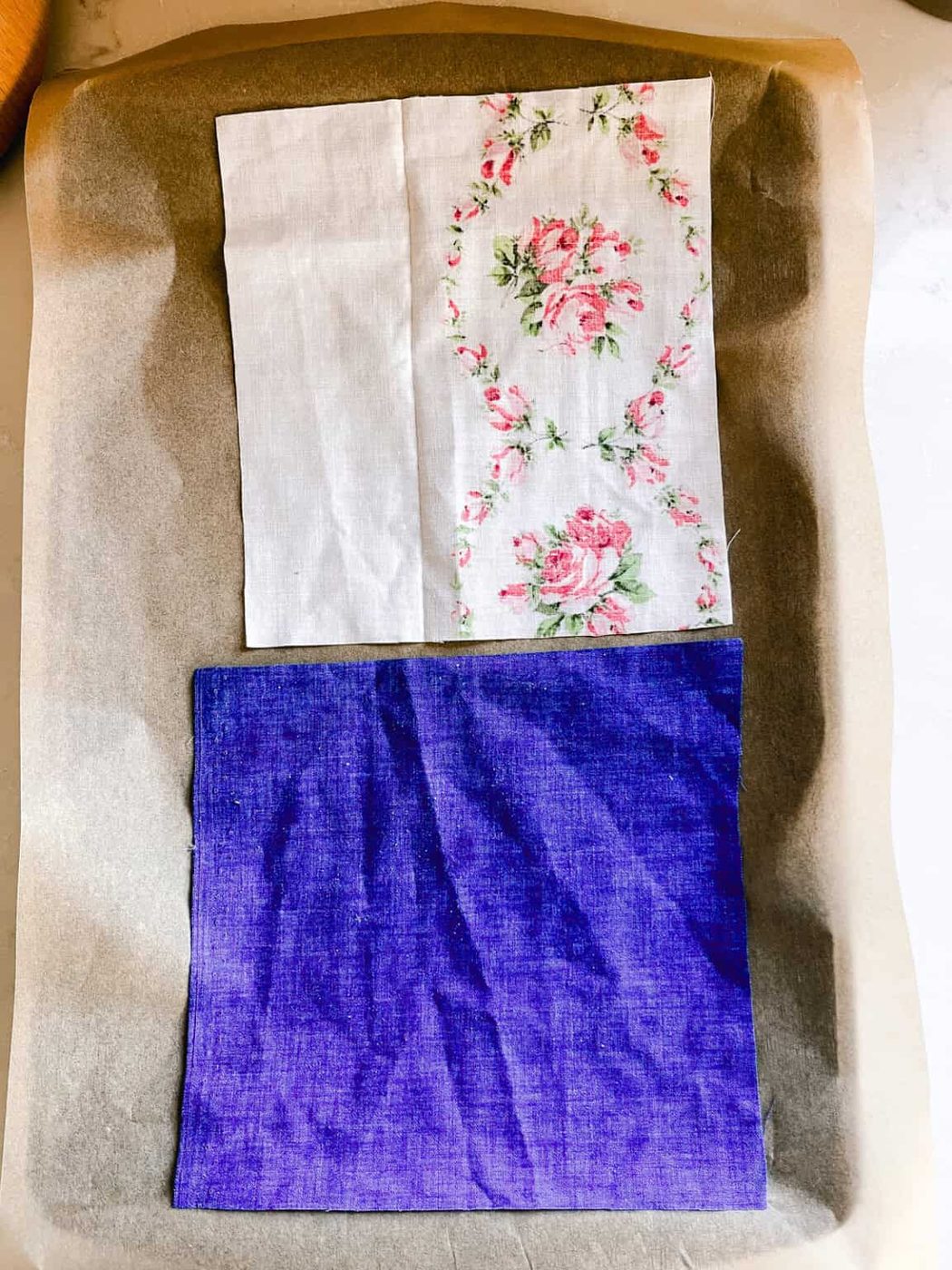 Laying fabric squares on a baking sheet lined with parchment paper.