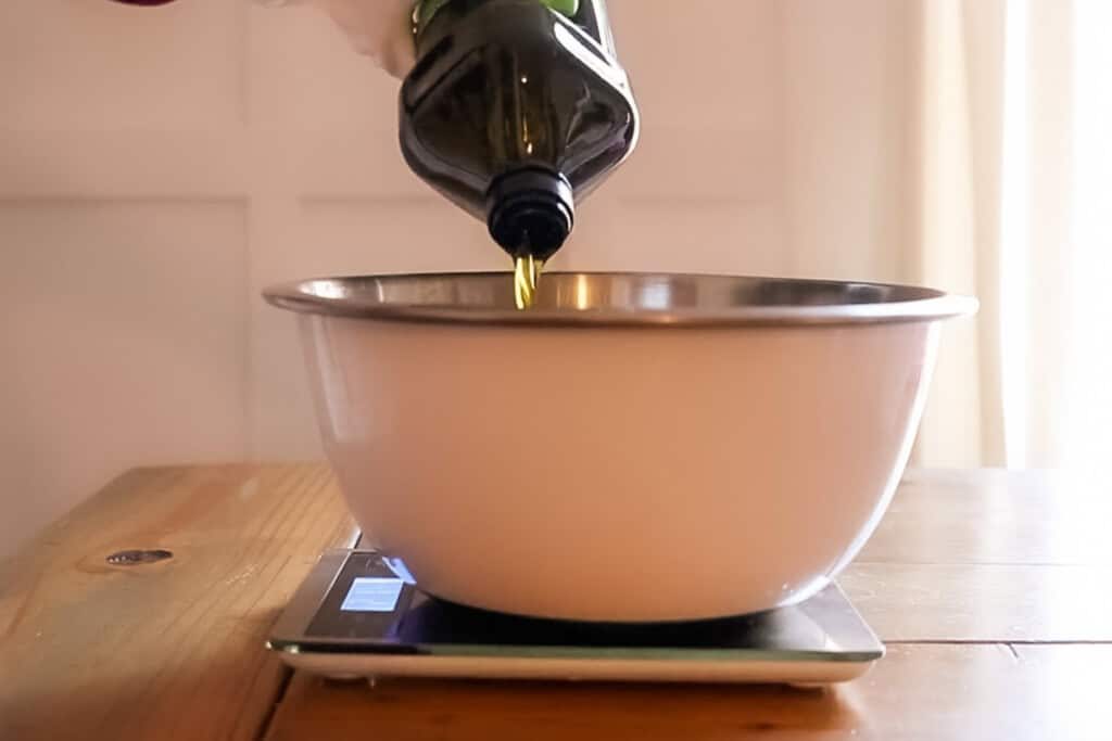 Pouring olive oil into a bowl with a digital scale.