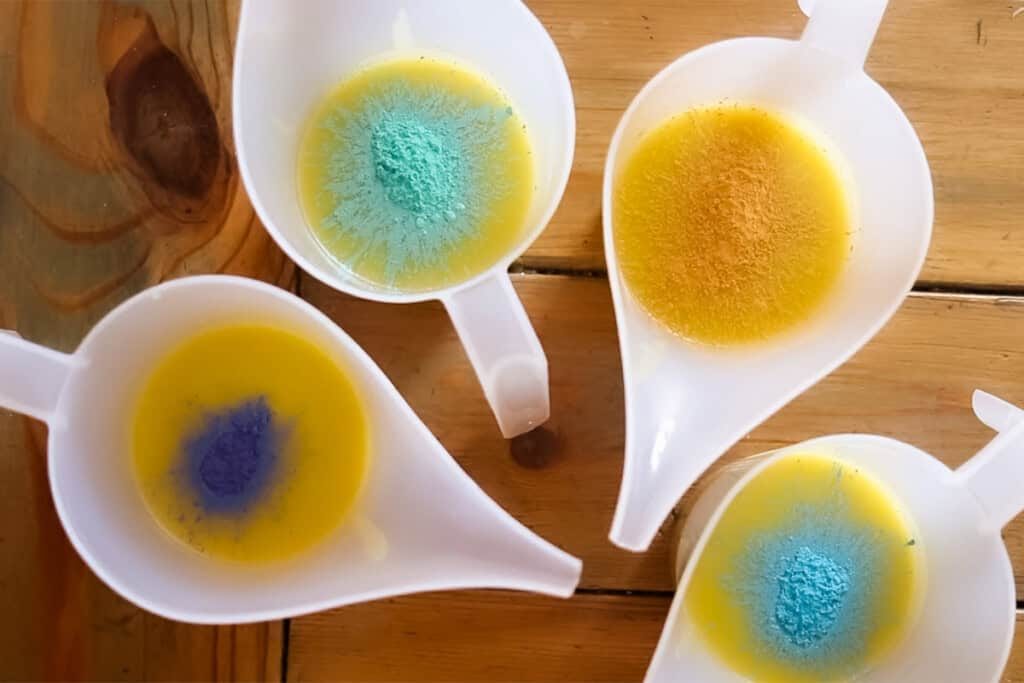 Soap mixture split into separate plastic pitchers with a different colorant in each pitcher.