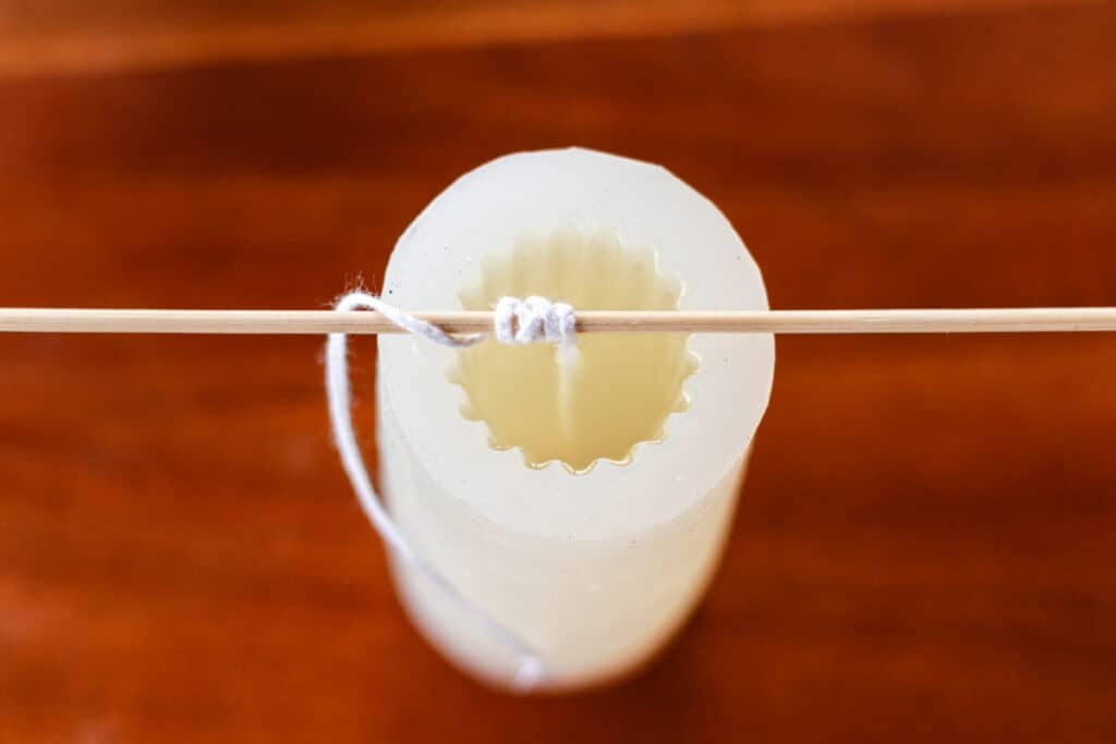 Wrapping the end of a wick around a bamboo skewer to hold it in its place while the wax melts.