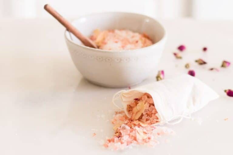 A bag of rose bath salts with a bowl in the background.