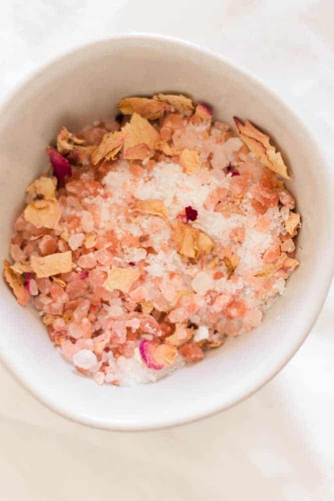 Rose petals and pink salt in small glass bowl.