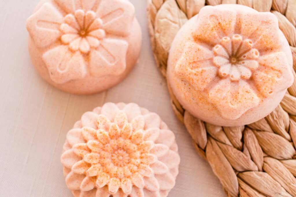 Flower-shaped orange soap bars on a wicker placemat.