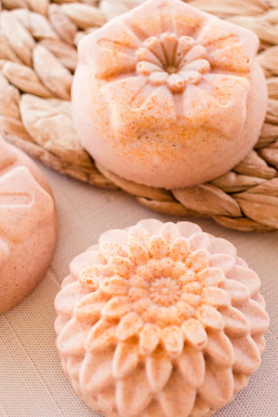 Flower-shaped orange soap bars on a wicker placemat.