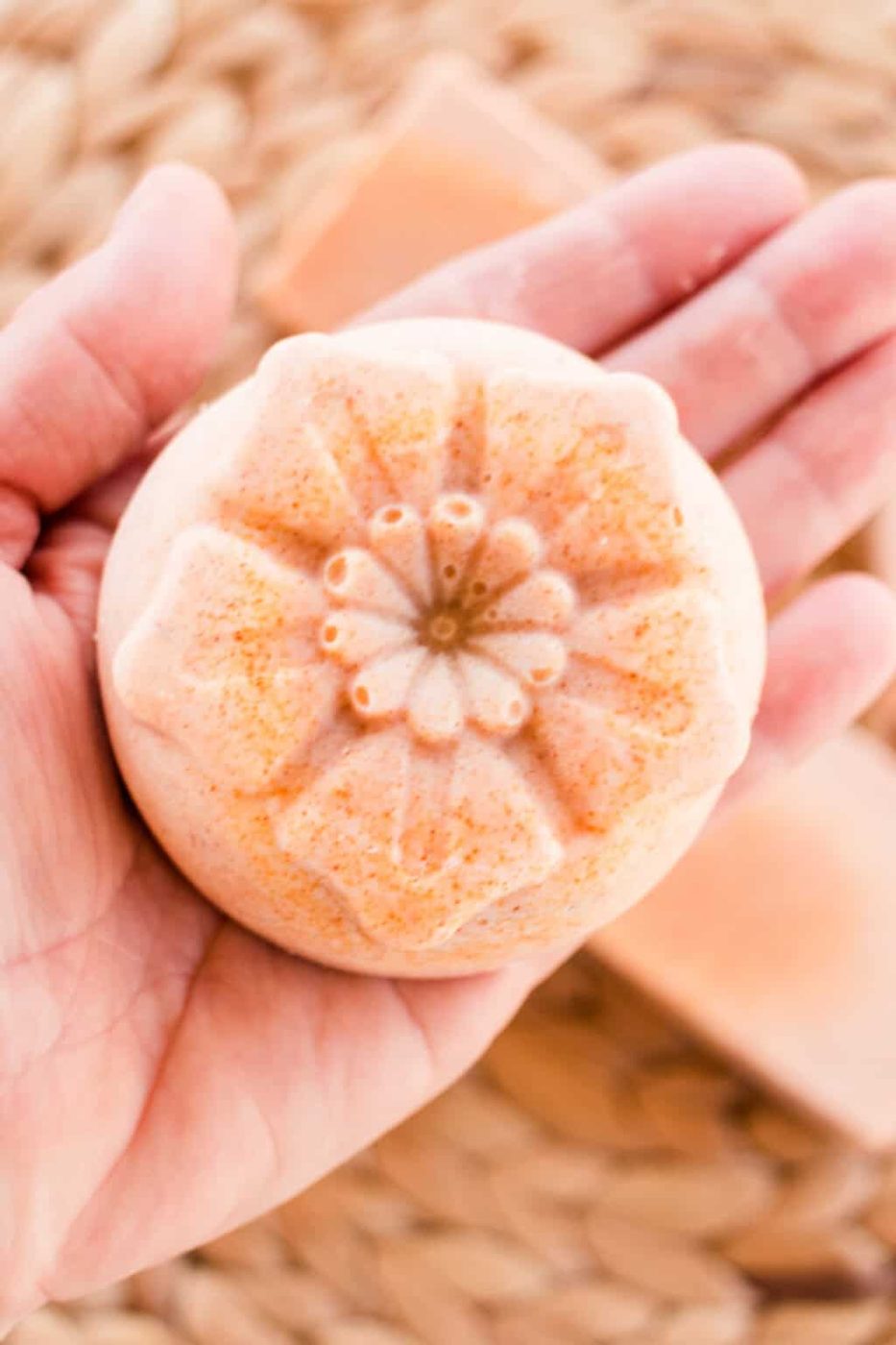 Holding a bar of flower-shaped soap.