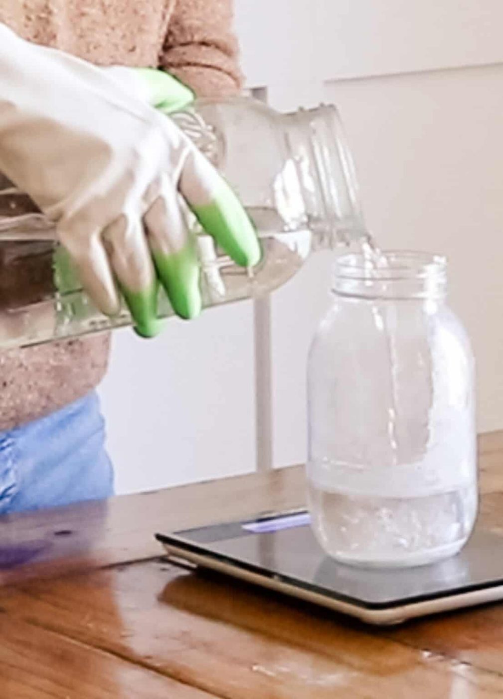 Pouring water into a glass jar on a digital scale.