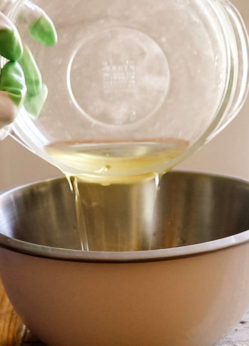 Pouring melted fats into a metal bowl.