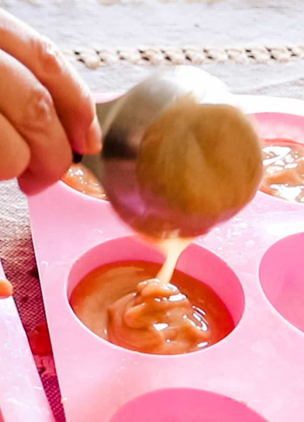 Scooping soap mixture into a silicone soap mold.