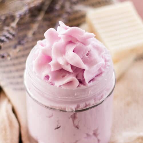 Fancy top soap with purple dye in a glass bowl with soap bars behind it.