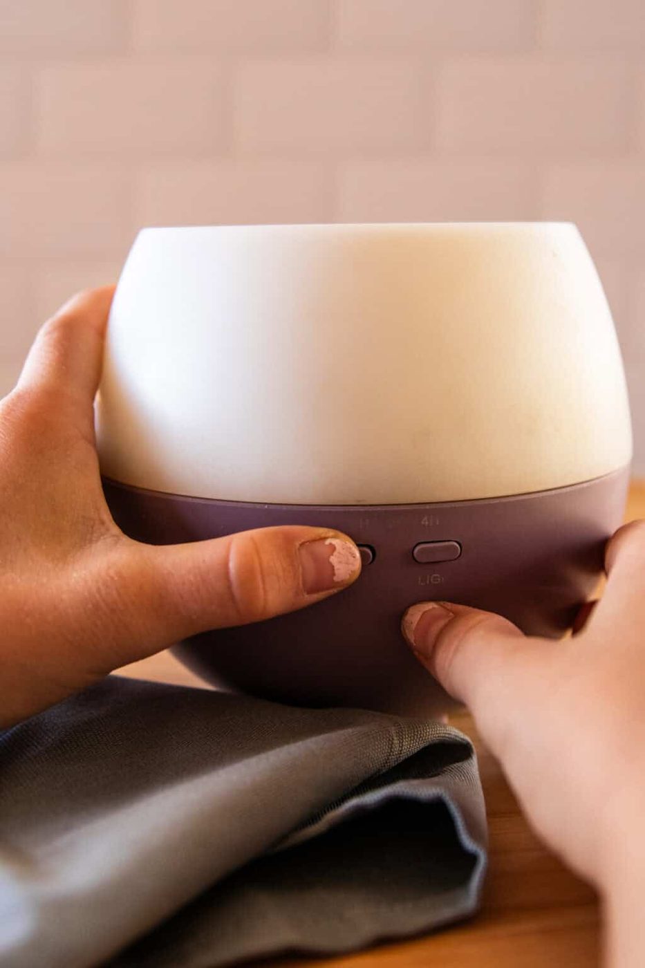 Pressing the start button on an essential oil diffuser.