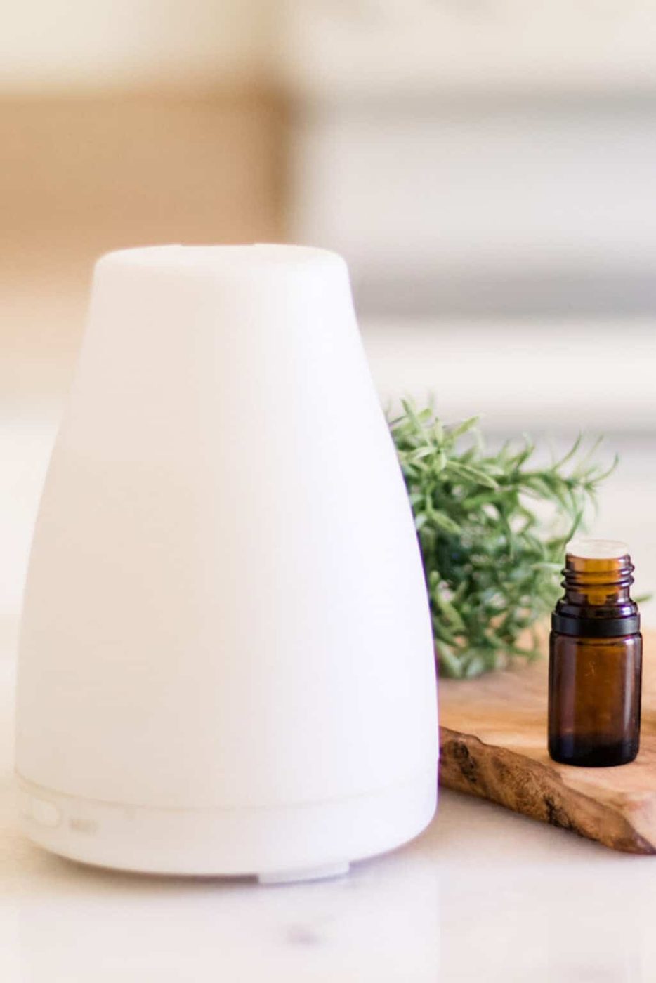 A diffuser on a white table with a bottle of essential oil.