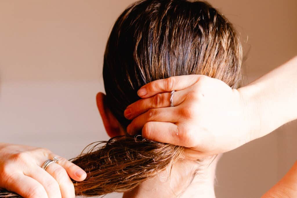 Working the castor oil hair mask into the strands of our hair.