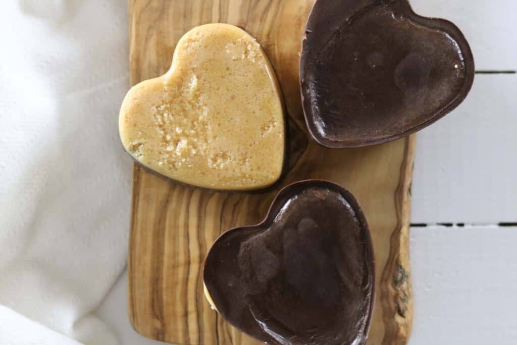 Paleo peanut butter chocolate hearts on white shiplap.