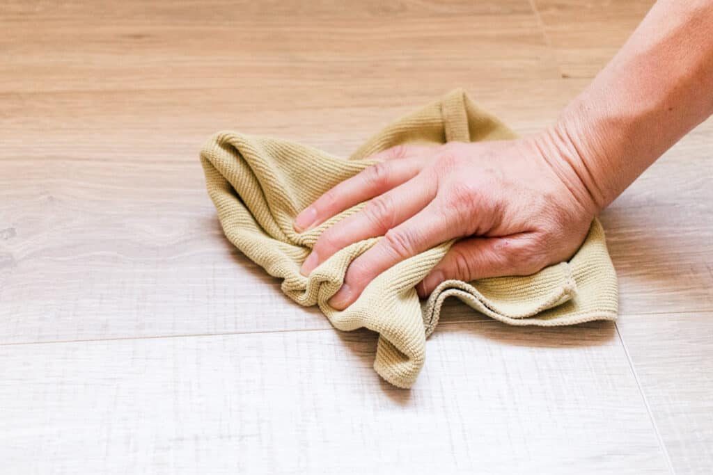 Buffing laminate flooring in a circular motion.