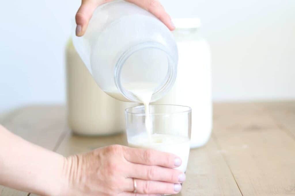 Purring raw milk from half gallon jar into glass cup.