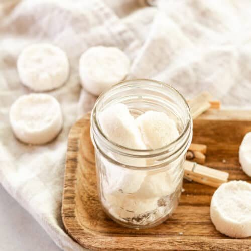 Homemade laundry soap pods drying on a towel and wooden tray.