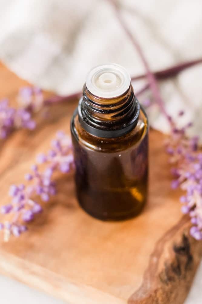 Bottle of lavender essential oil with lavender sprigs around it.