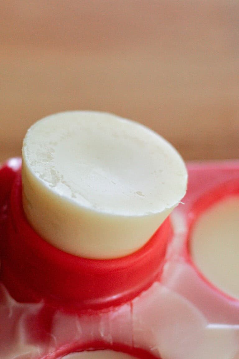 A lotion bar being popped out of a silicone mold after hardening completely.