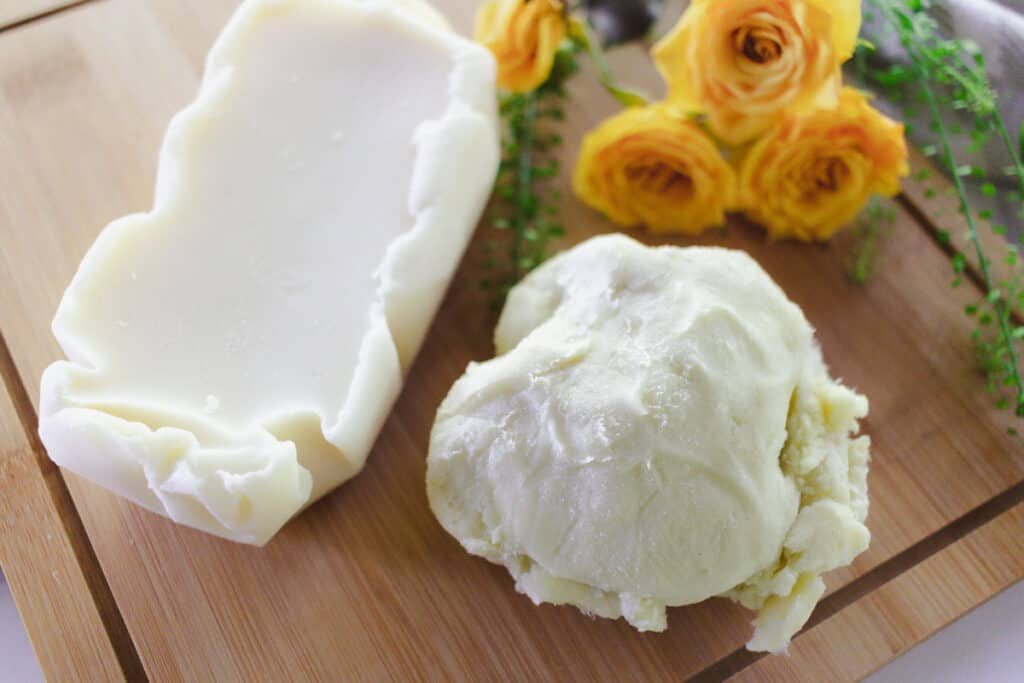 Mango butter and shea butter on a wooden board.