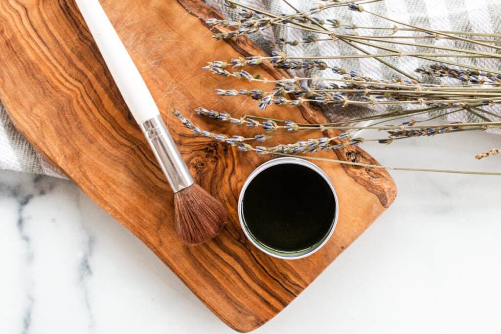 Matcha face mask brush with a tin of matcha mask paste on a marble vanity.