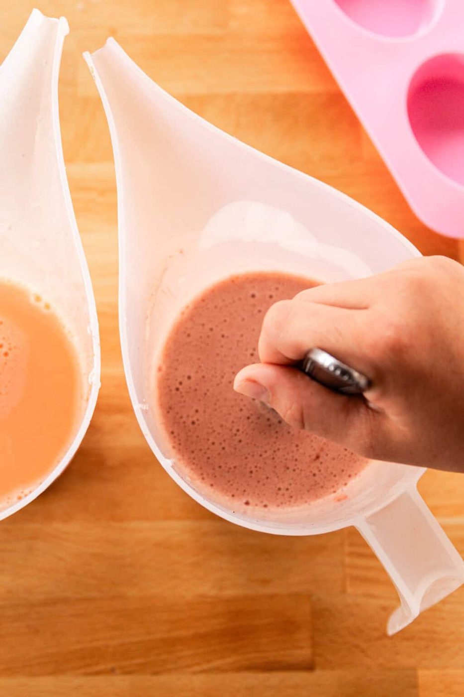 Mixing mica powder into melted soap base in a plastic pouring cup.