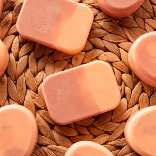 Bars of orange creamsicle soap spread on a wicker background.