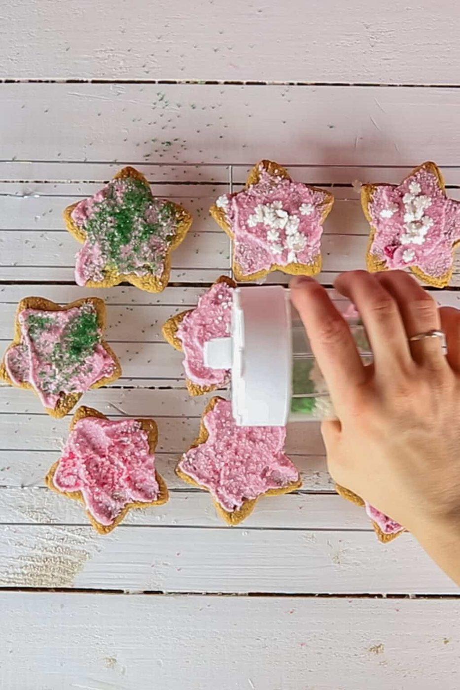 Shaking sprinkles onto frosted sugar cookies.