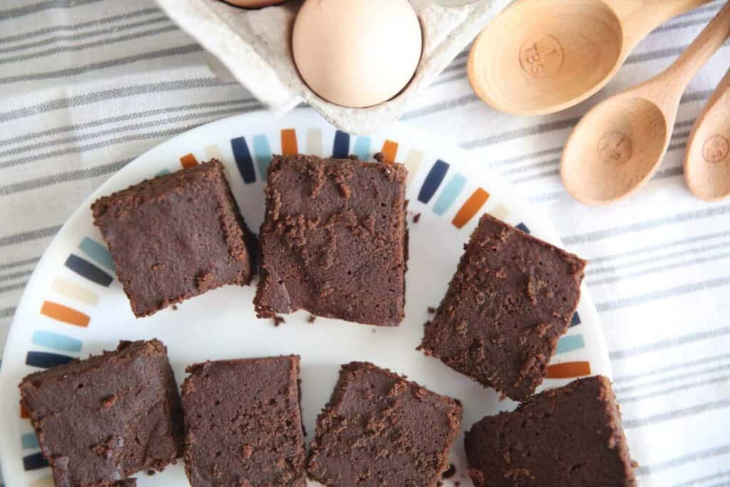 Paleo brownies on plate with wooden measuring spoons in background.