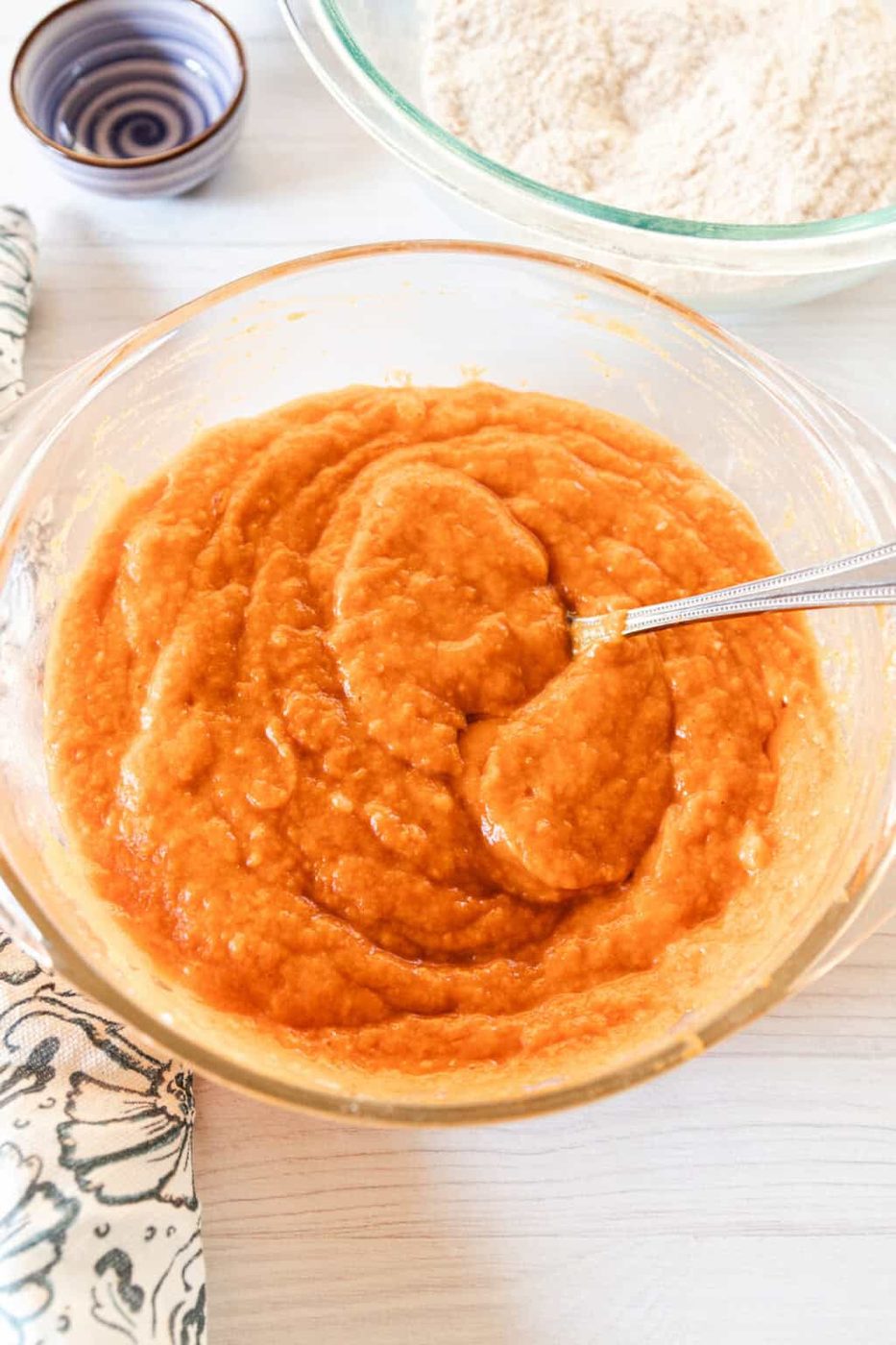 Mixing together the wet ingredients for the pumpkin bread in a glass mixing bowl.