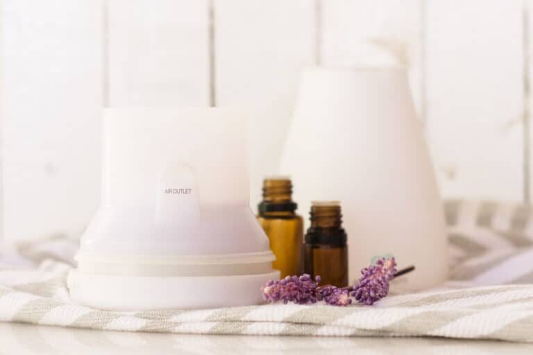 A diffuser with bottles of essential oils and a lavender sprig.