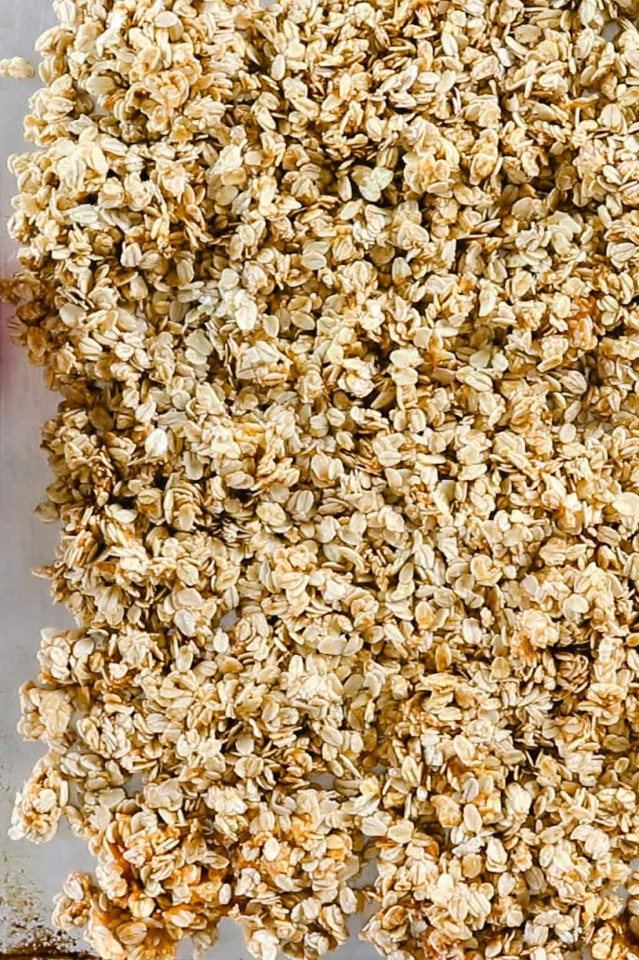 Spreading pumpkin granola on a sheet pan to bake.