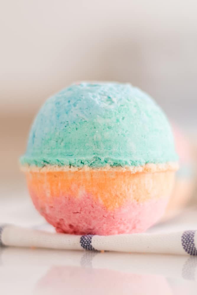 Large multicolor bath bomb for kids on white marble table.