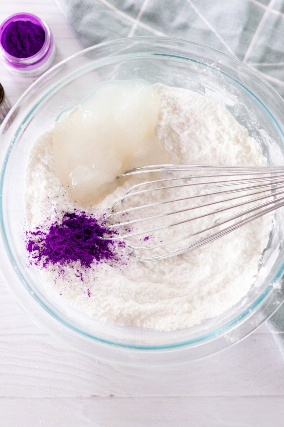 Bath bomb ingredients in a glass bowl with a whisk.