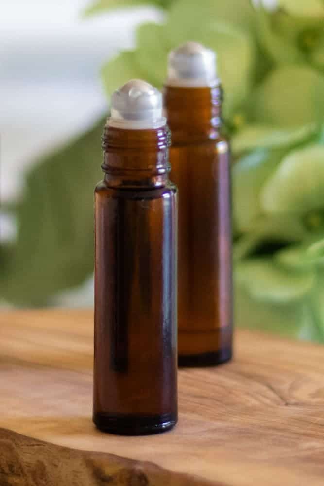 Two amber colored essential oil roller bottles with the lids off.