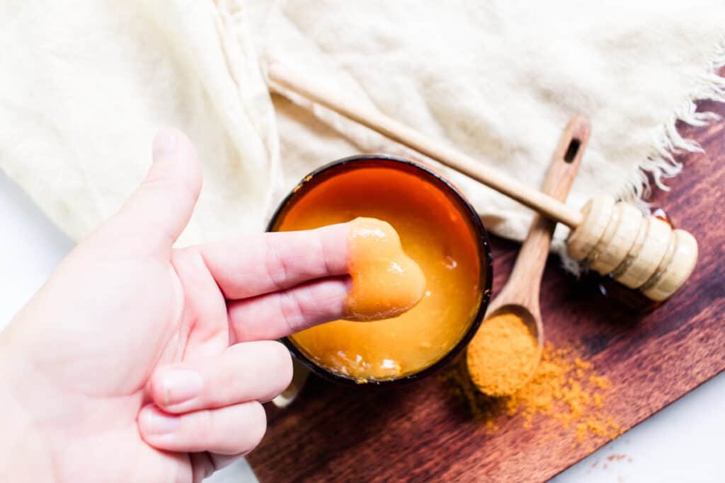 Applying sea moss face mask to the face using two fingers.