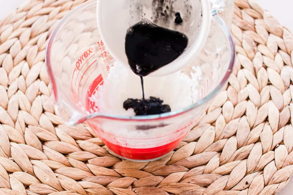 Adding charcoal powder to a mixing jug.