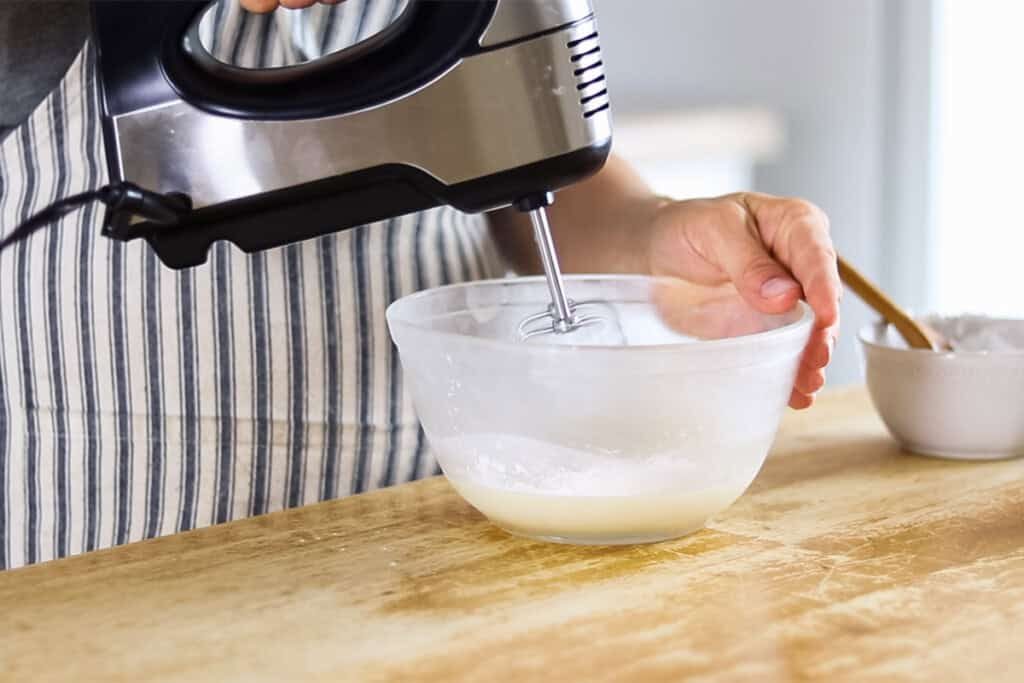 Using a hand mixer to whip the shea butter lotion ingredients.
