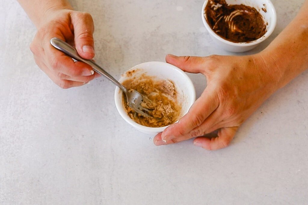 Stirring a bowl of cinnamon and shea butter to create homemade lip plumper.