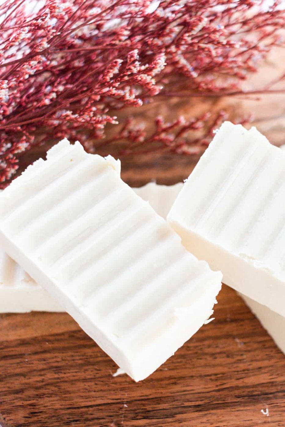 Several homemade shea butter soap bars with textured sides on a wooden block.