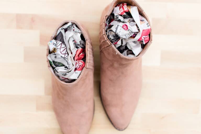 Brown women boots with newspaper stuffed inside them to dry them out.