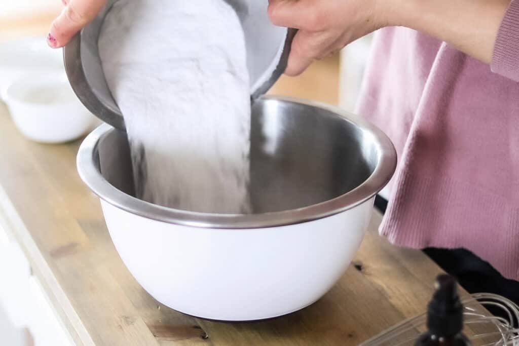 Pouring the dry ingredients for the bath bombs into a large mixing bowl.