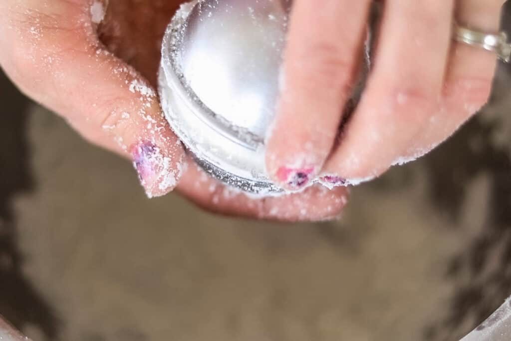 Filling molds with the bath bomb mixture and pressing it together firmly.